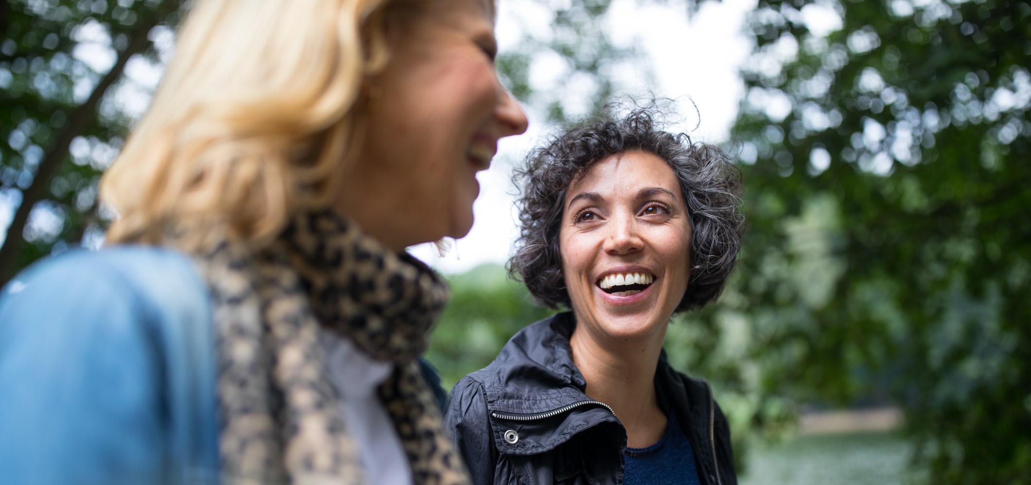 Two women smiling and talking with each other whilst out on a walk