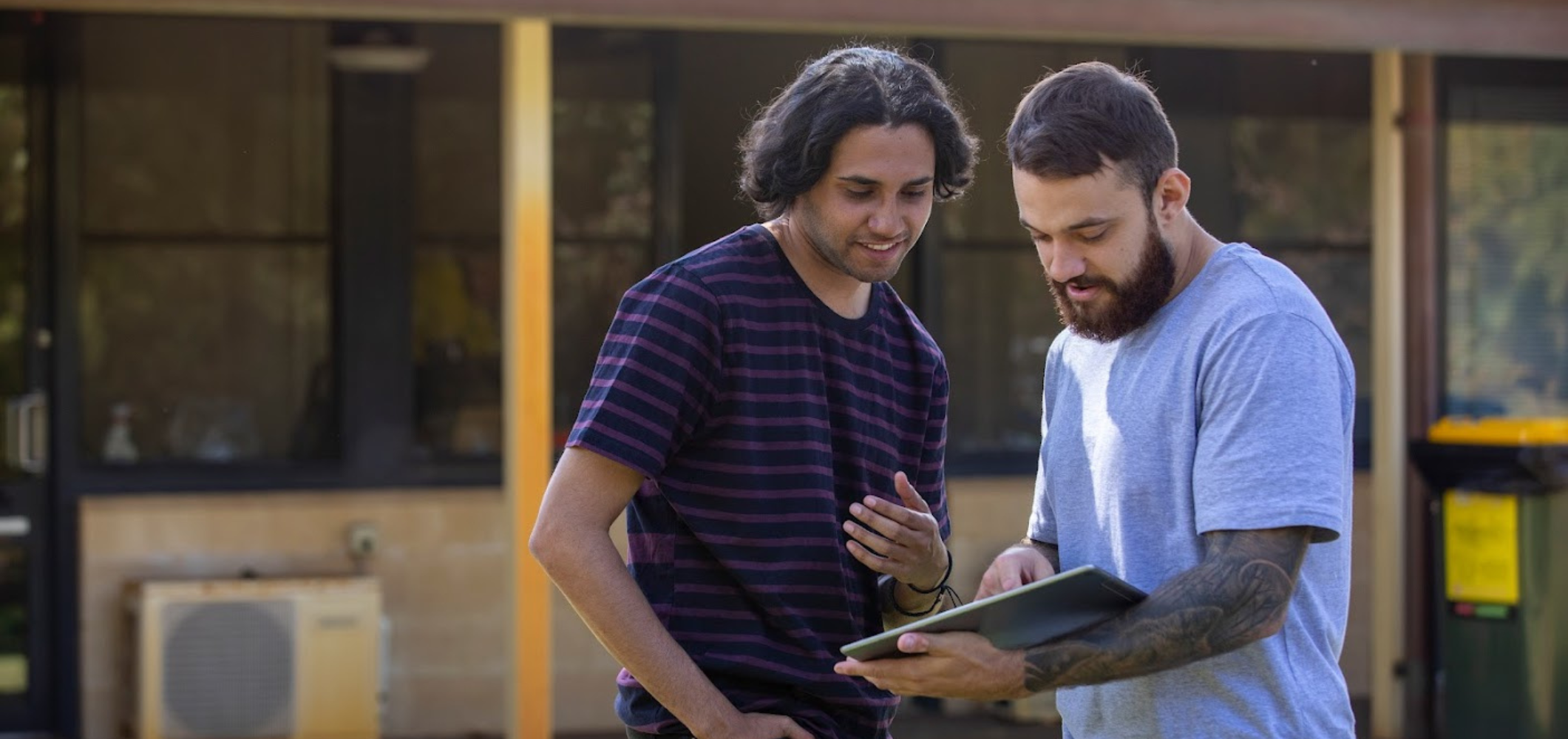 Two men talking with each other outside whilst referring to a document