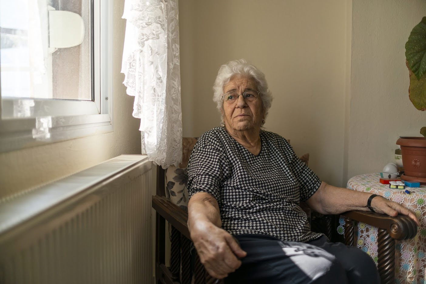 Older woman sitting in chair and looking out the window.