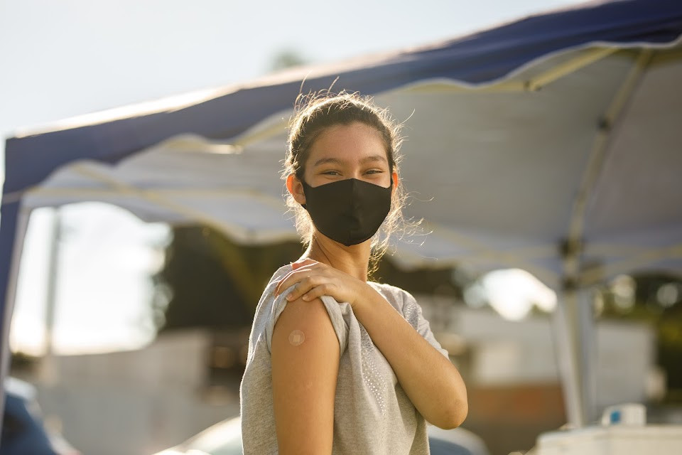 Girl showing bandaid on arm after receiving vaccination.