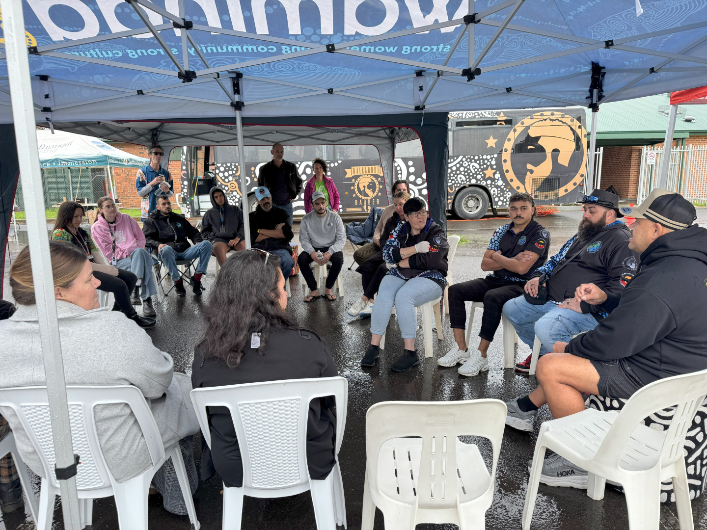 Local community members sitting in a circle talking at event.