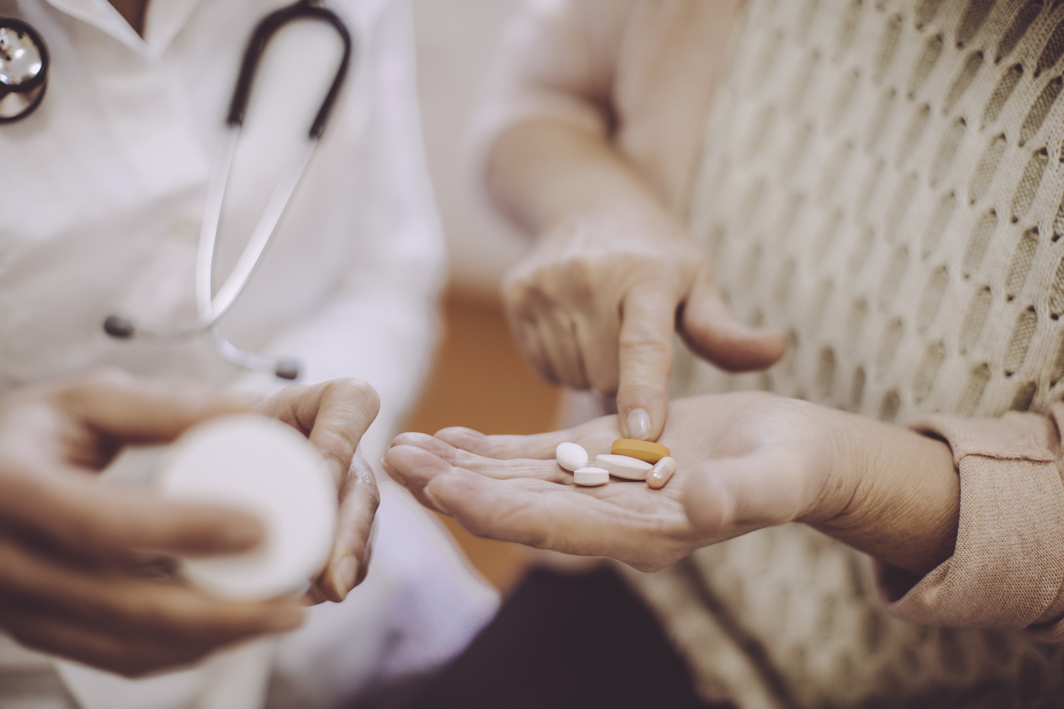 Elderly person holding hand out with medication in their hand 