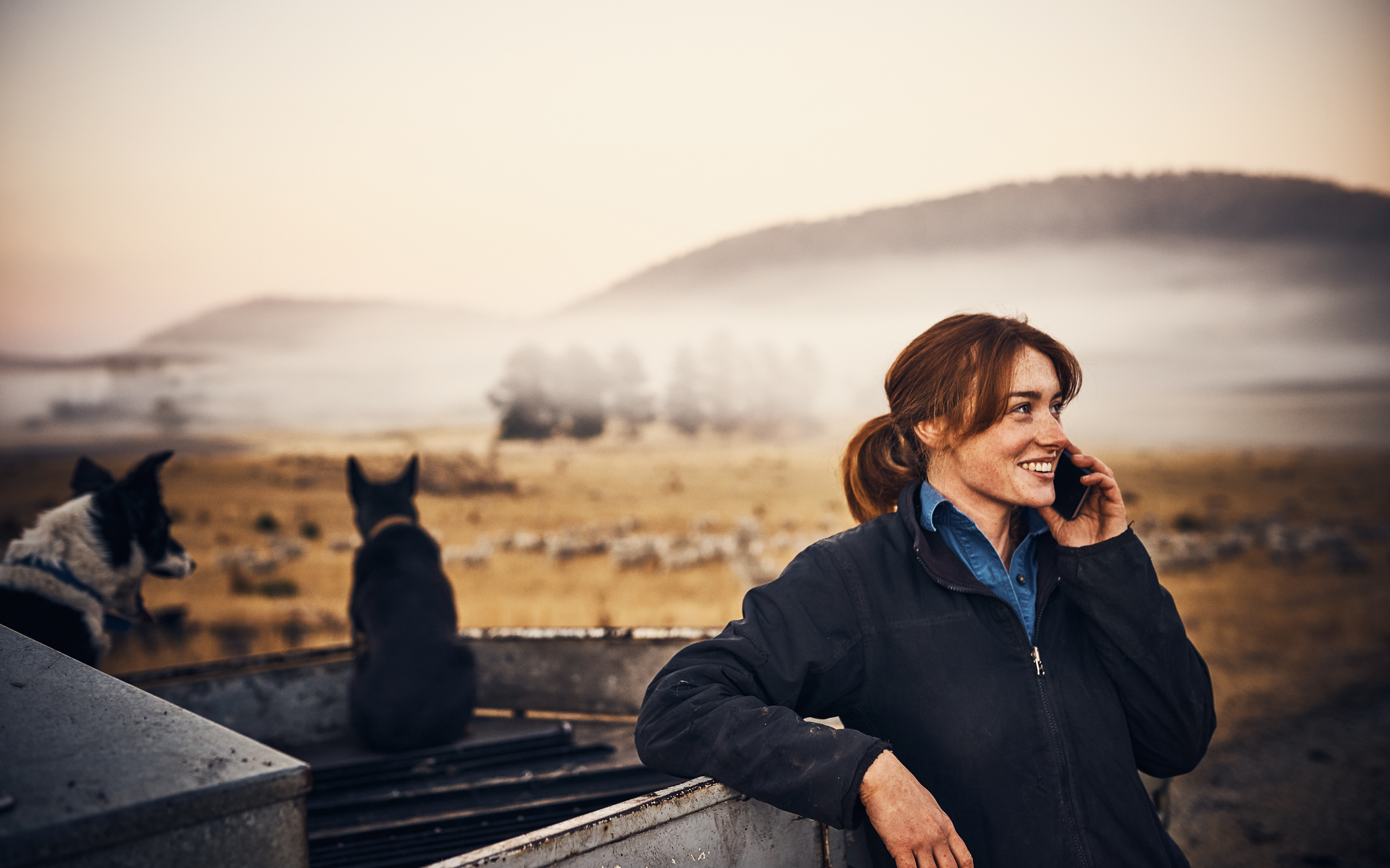 A woman leaning on a ute speaking on the phone