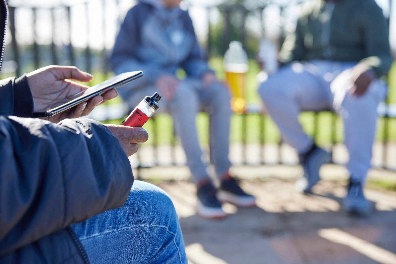 People sitting near a park vaping