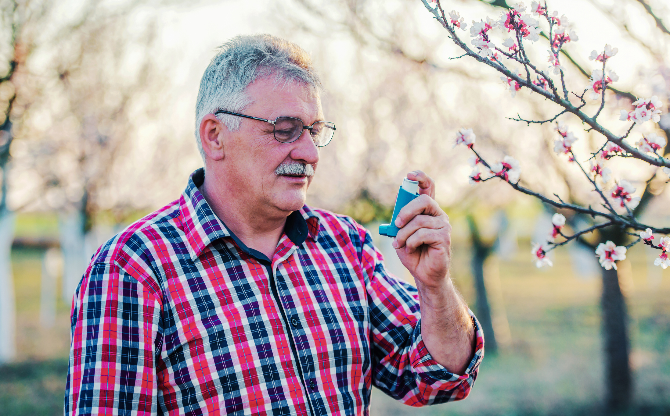 Elderly man using an inhaler outside