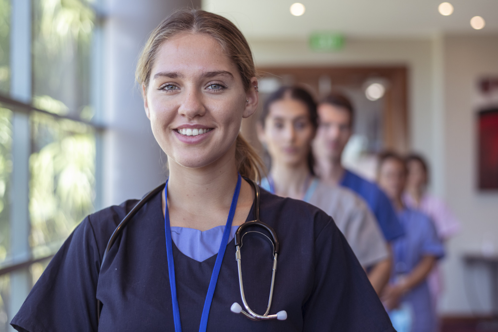 Several nurses standing in a line dressed in different uniforms smiling at the camera