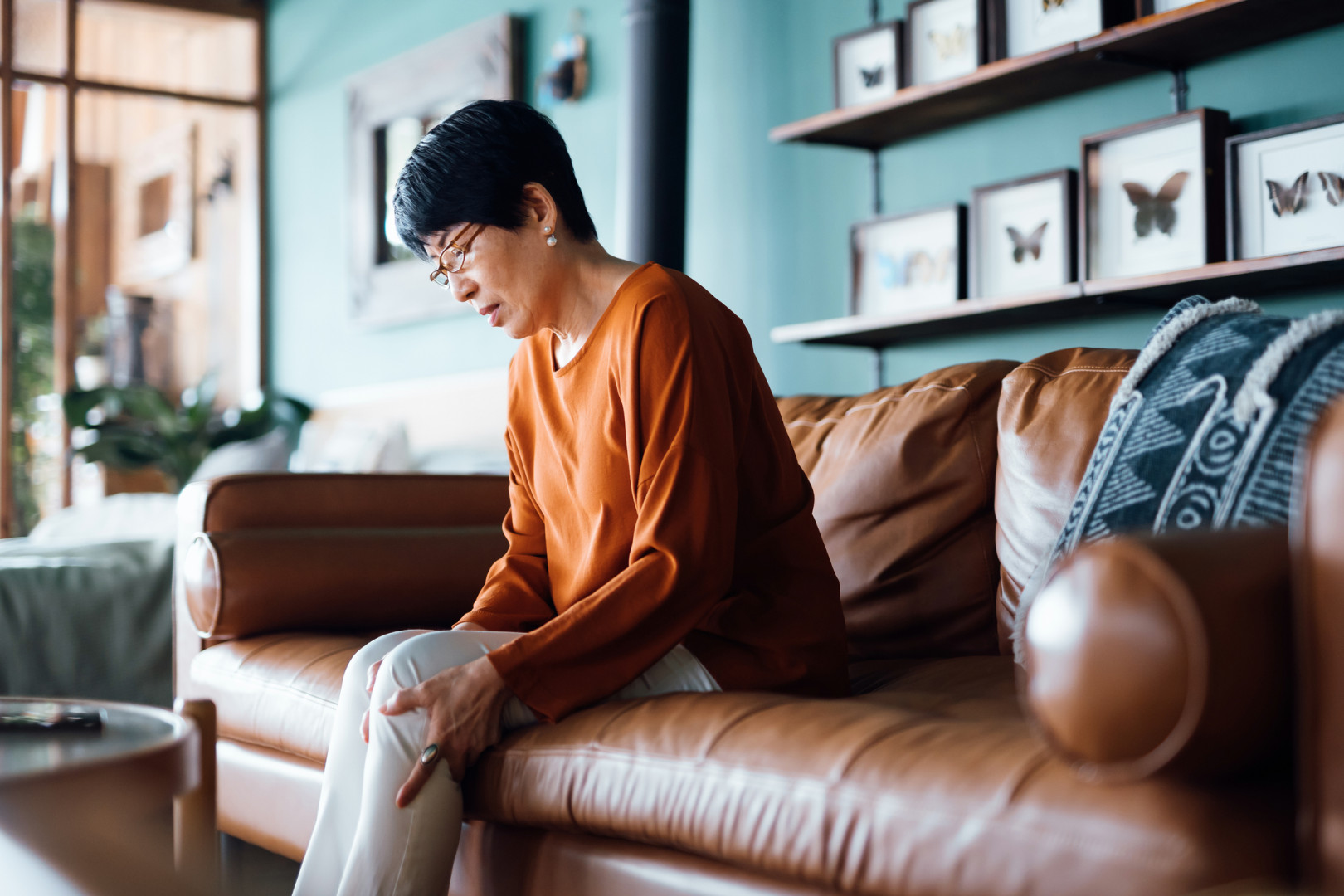 Elderly lady sitting on a couch with leg pain.