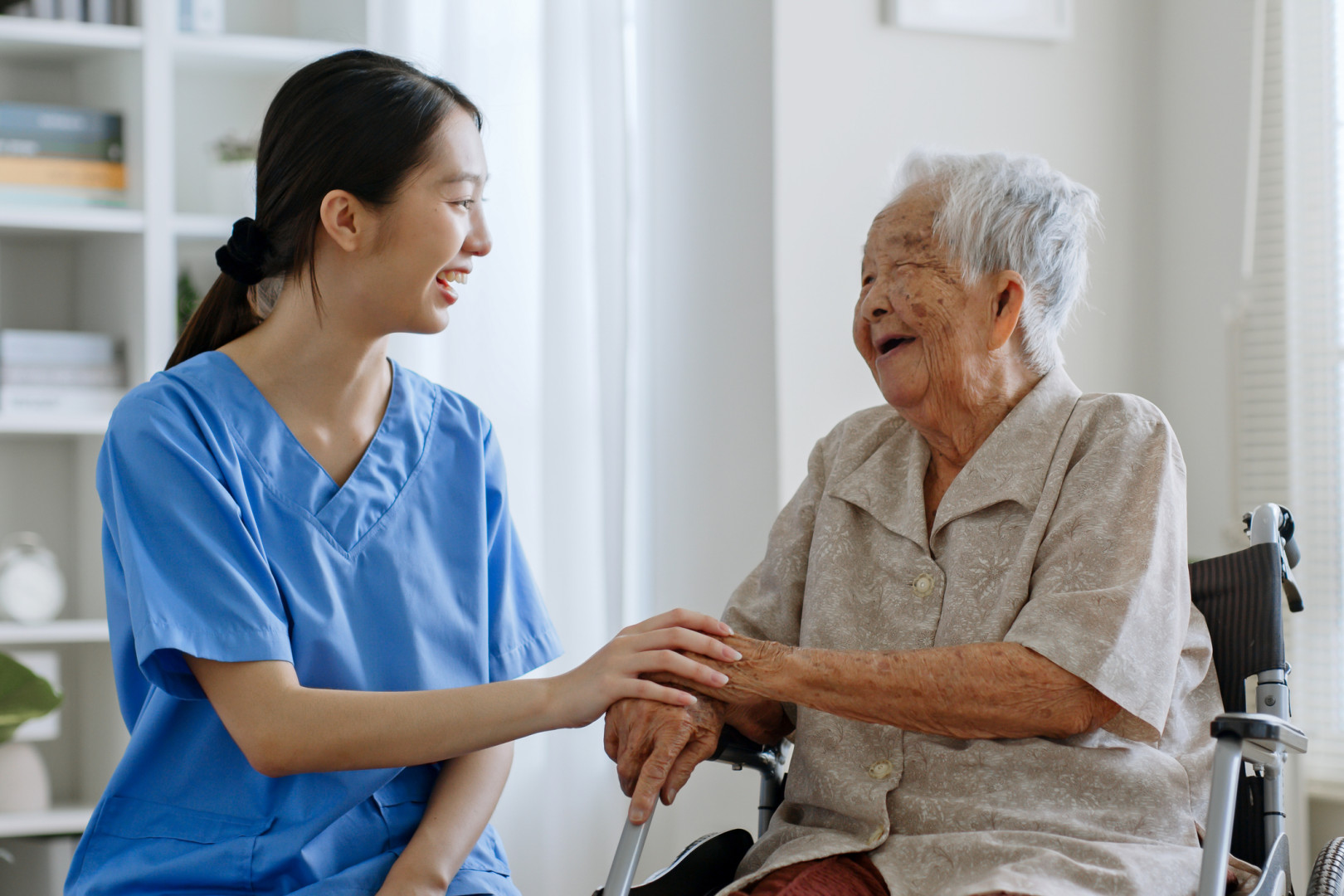 Nurse speaking with an elderly person sitting in a wheel chair
