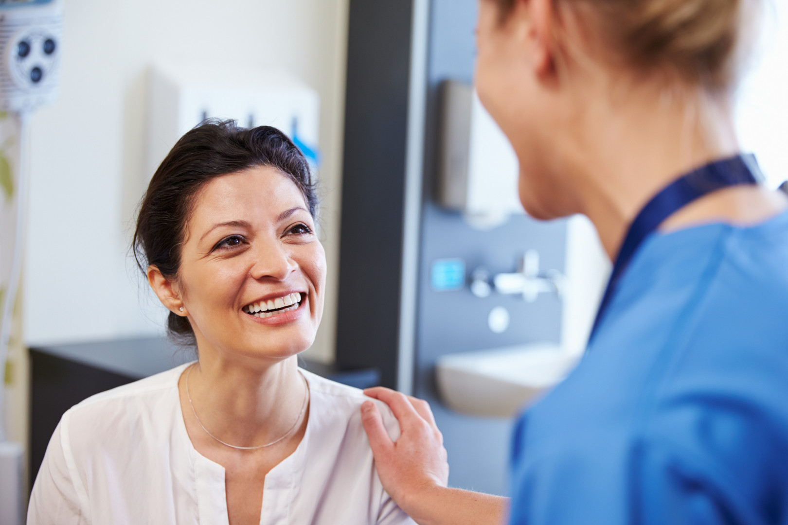 A middle aged woman smiling whilst talking to a nurse.