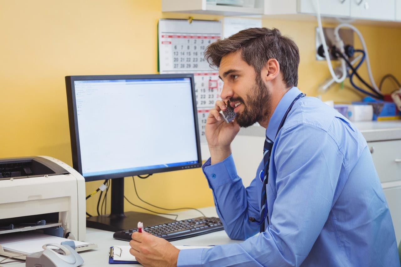 GP on phone in front of a computer.