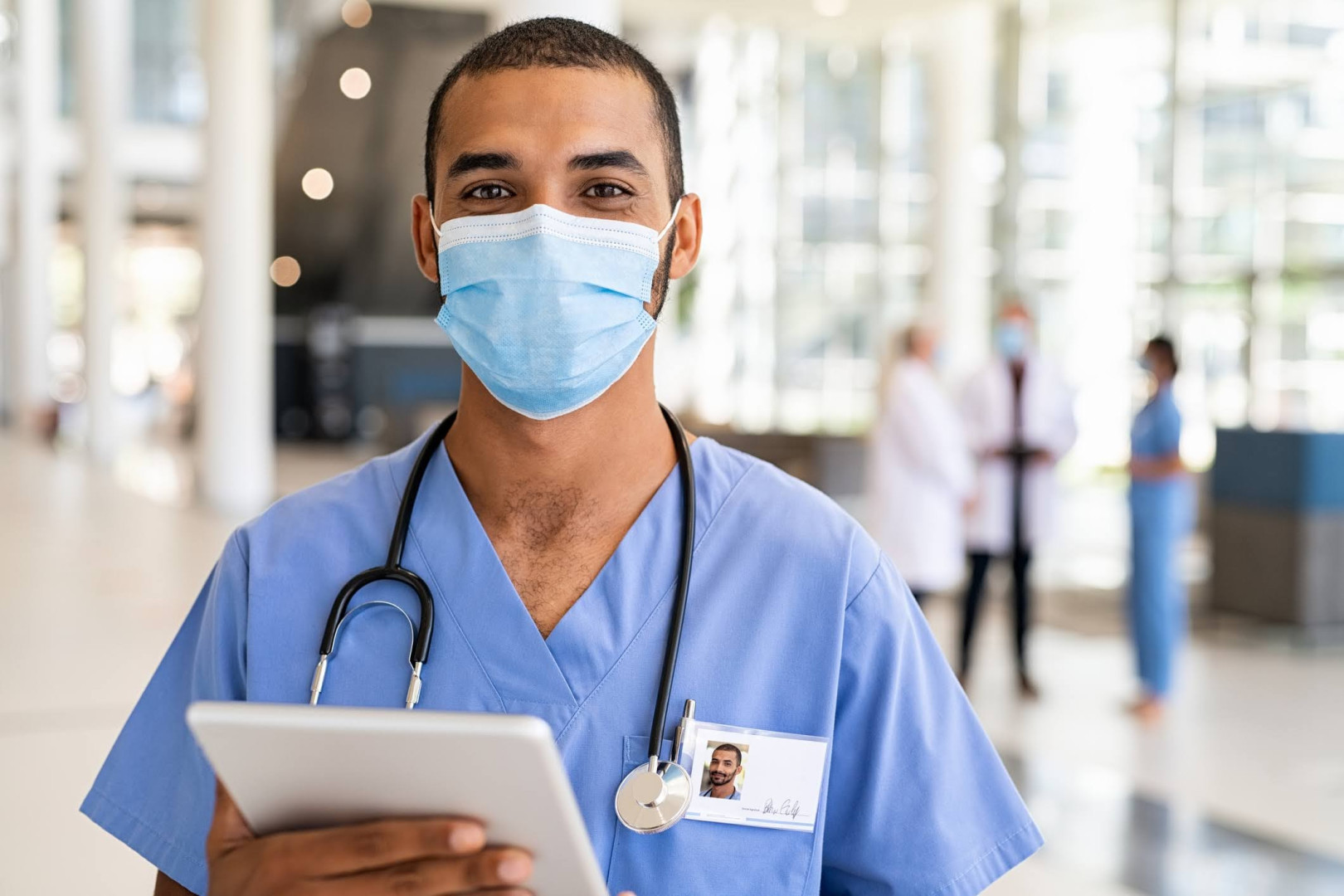 Male nurse, wearing surgical mask.