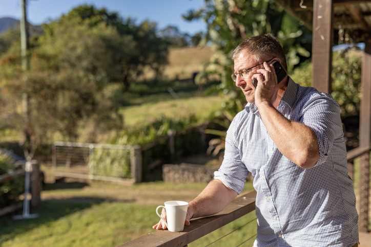Man looking out from balcony while on the phone.