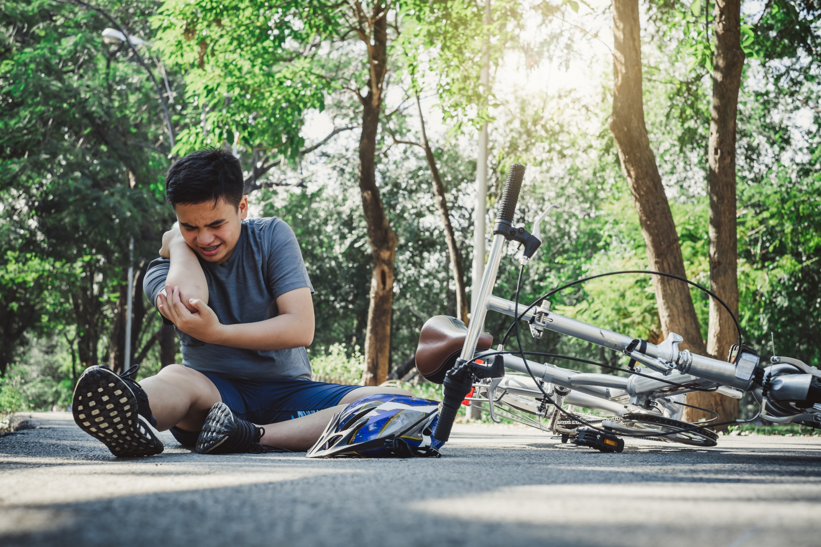 Young teen holding arm, after falling off bicycle.